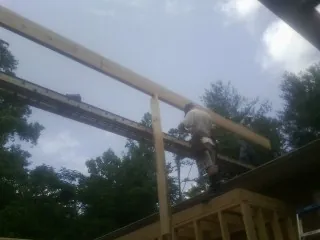 Carpenter setting a ridge beam over a new addition frame — Ice Dam Removal by Roofing Brothers in North Greece