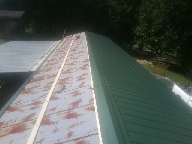 Old rusted panels beside newly installed green metal roofing — Wind Damage Roof Repair by Roofing Brothers in North Greece