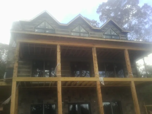 Dormers and porch framing on a large log home under construction — Roof Coating work by our crew in North Greece