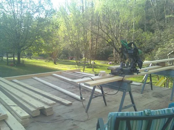 Miter saw and framing lumber on a deck under construction in North Greece