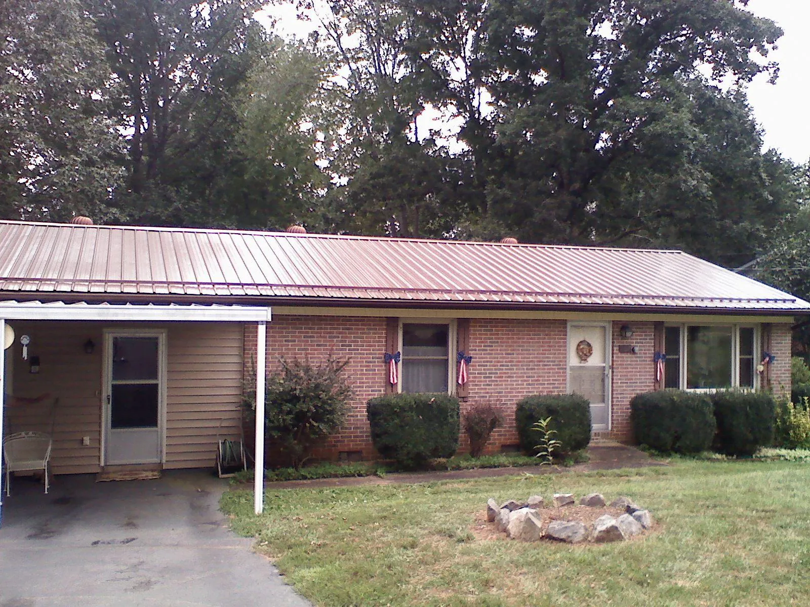 Bronze metal roof and carport on a brick ranch home — Roof Repair work by our crew in North Greece