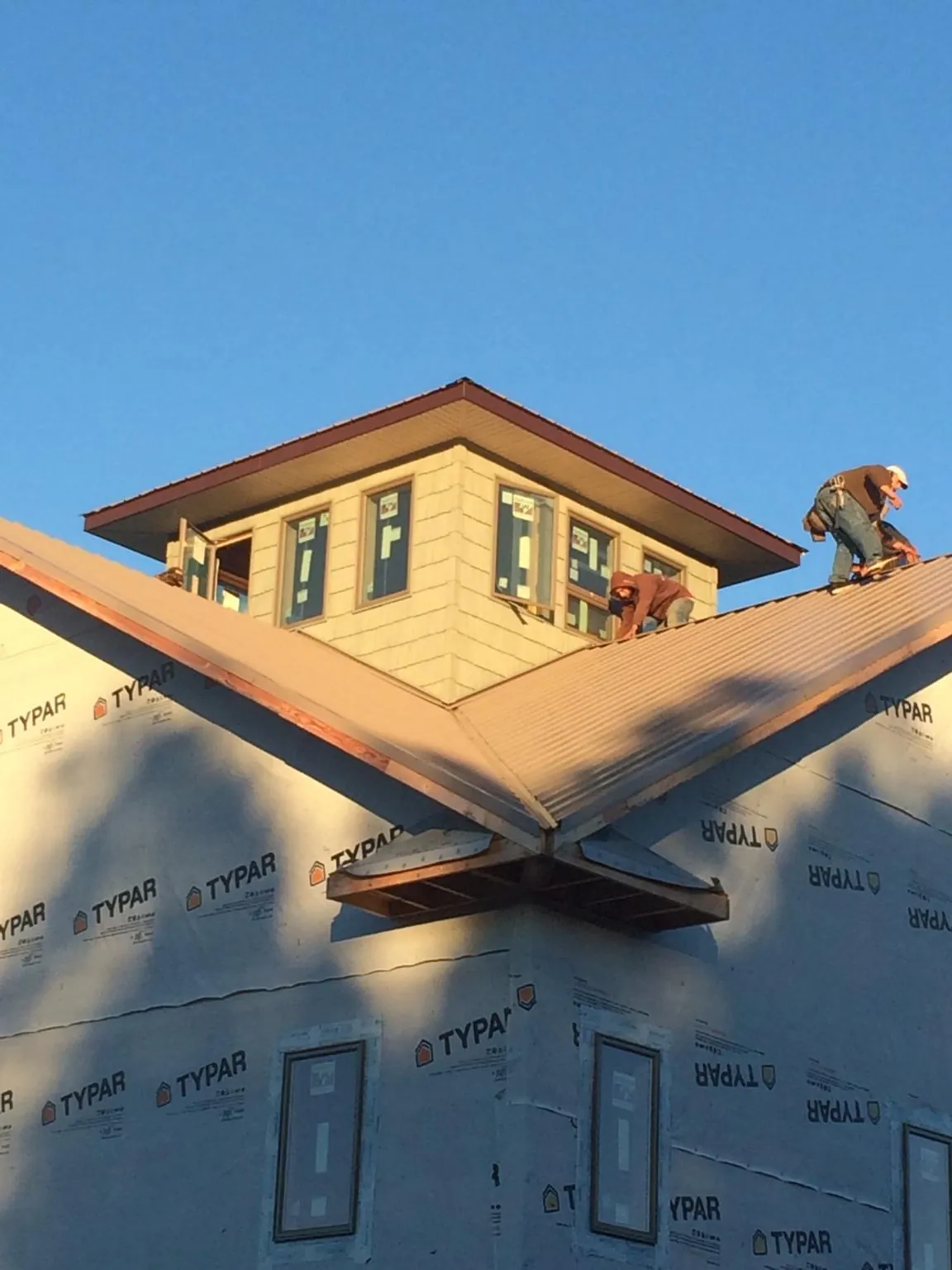 Roofers working around a rooftop cupola on a new metal roof at sunset — Roof Waterproofing in North Greece by Roofing Brothers